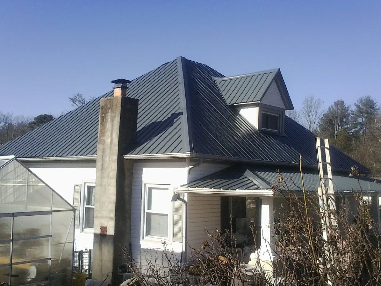 Dark blue standing seam metal roof on a white farmhouse with dormer — Slate & Tile Roof Repair by Roofing Brothers in Battle Mountain