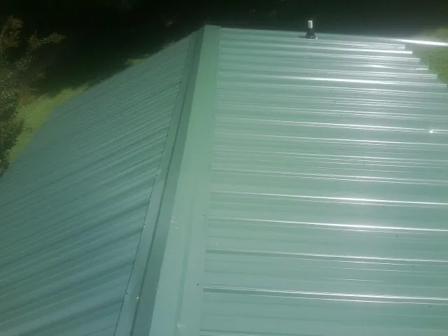 New green metal panels meeting at the ridge of a roof — Flat Roof Repair work by our crew in Battle Mountain