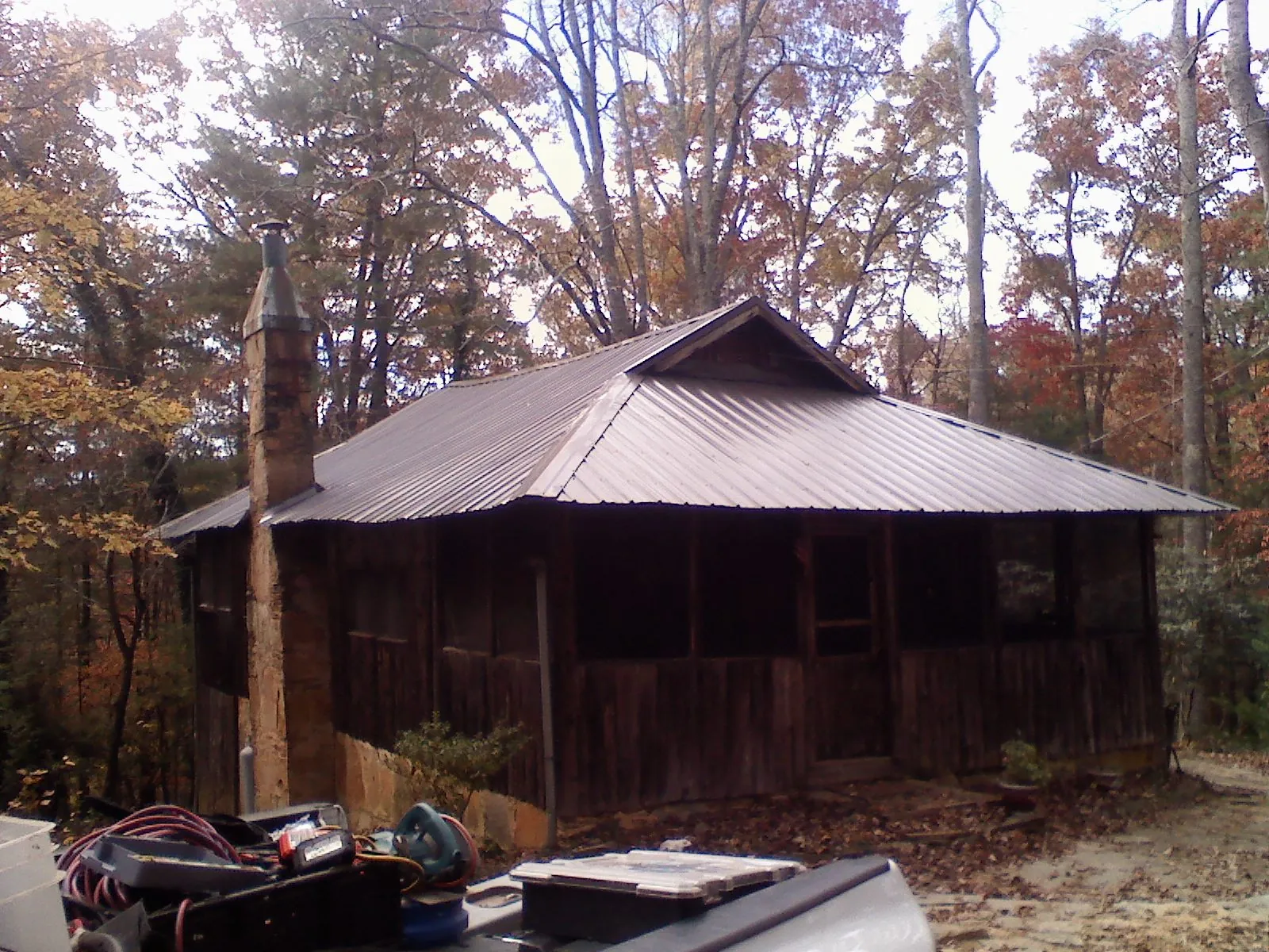 Brown metal hip roof on an old cabin with a stone chimney in Battle Mountain