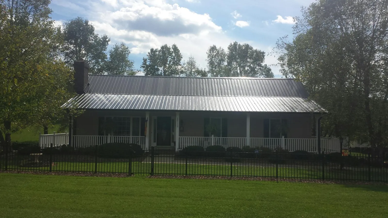 Gray metal roof on a brick ranch with a full width front porch — Gutter Guard Installation work by our crew in Battle Mountain