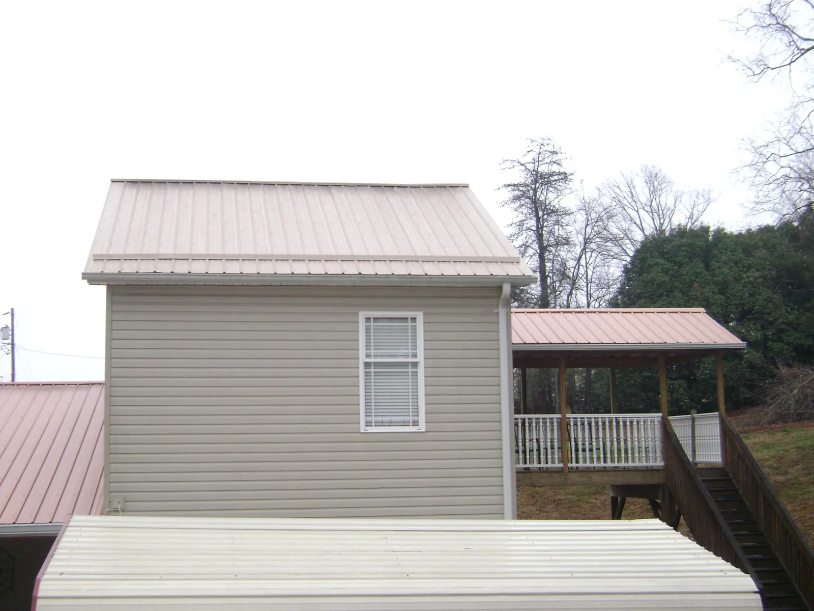 Tan metal roofs on a two story addition and attached porch, from a Roof Replacement job in Battle Mountain