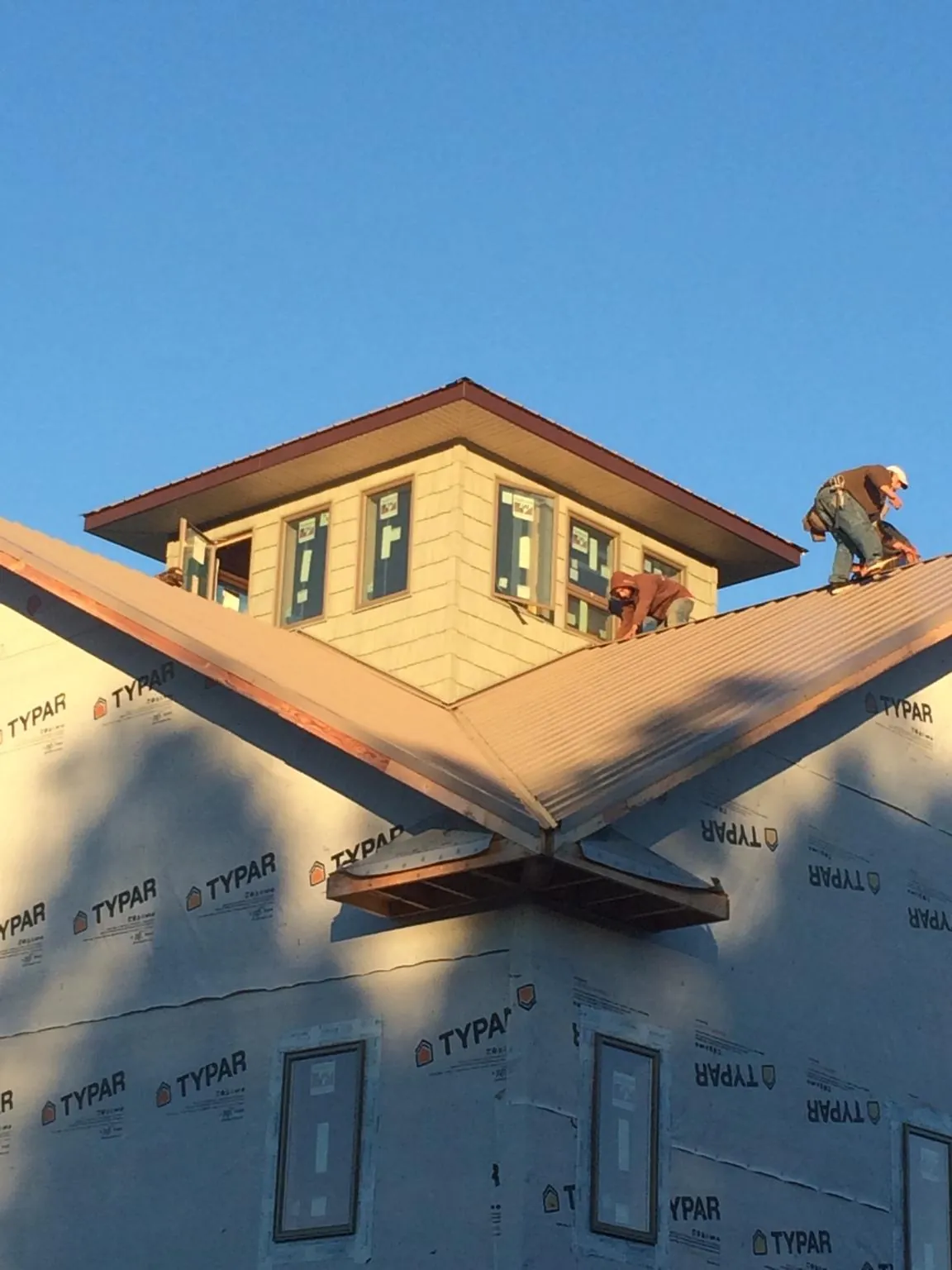 Roofers working around a rooftop cupola on a new metal roof at sunset — Roof Waterproofing in Battle Mountain by Roofing Brothers